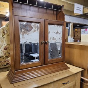A wooden wall-mounted mirrored cabinet with a built-in top hat/coat (092694)